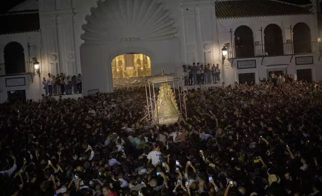 Pilgrims carry the Virgin of El Rocio outside the shrine in El Rocio, near Almonte in southern Spain, on Monday, June 9, 2025, during the annual pilgrimage in which hundreds of thousands of devotees of the Virgin del Rocio converge in and around the shrine. (AP Photo/Emilio Morenatti)
