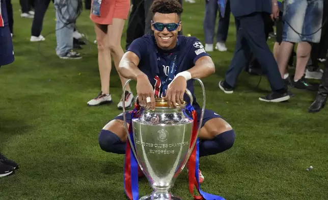 PSG's Desire Doue poses with the trophy after the Champions League final soccer match between Paris Saint-Germain and Inter Milan at the Allianz Arena in Munich, Germany, Saturday, May 31, 2025. (AP Photo/Matthias Schrader)