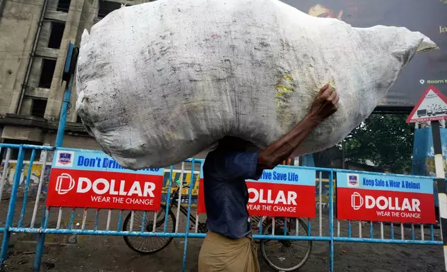 A labourer carries a huge sack of vegetables on way to a market in Kolkata, India, Thursday, June 26, 2025. (AP Photo/Bikas Das)