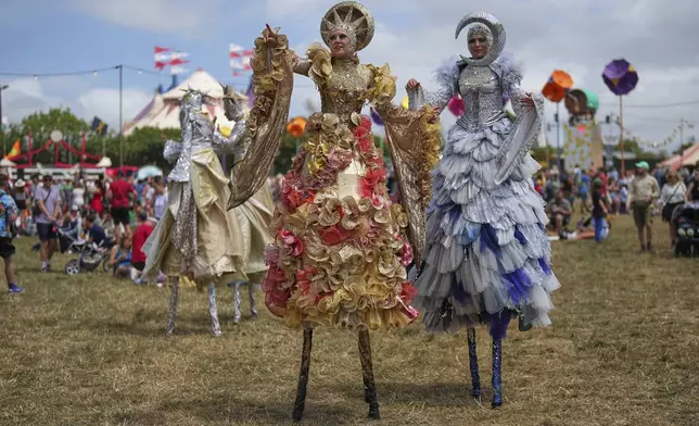 Stilt walkers make their way through the Glastonbury Festival in Worthy Farm, Somerset, England, Thursday, June 26, 2025. (Scott A Garfitt/Invision/AP)