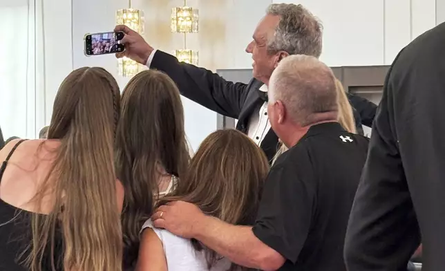 Health and Human Services Secretary Robert F. Kennedy Jr. takes a photo with people at the opening night of "Les Miserables," at the Kennedy Center, Wednesday, June 11, 2025, in Washington, that President Donald Trump and first lady Melania Trump were also attending. (AP Photo/Alex Brandon)