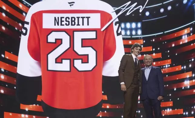 Jack Nesbitt, left, stands with NHL commissioner Gary Bettman after being drafted by the Philadelphia Flyers during the NHL hockey draft Friday, June 27, 2025, in Los Angeles. (AP Photo/Damian Dovarganes)