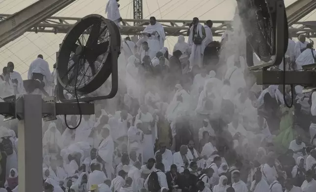 Cooling fans spray water over Muslim pilgrims gathered atop the rocky hill known as the Mountain of Mercy, on the Plain of Arafat, during the annual Hajj pilgrimage near the holy city of Mecca, Saudi Arabia, Thursday, June 5, 2025. (AP Photo/Amr Nabil)