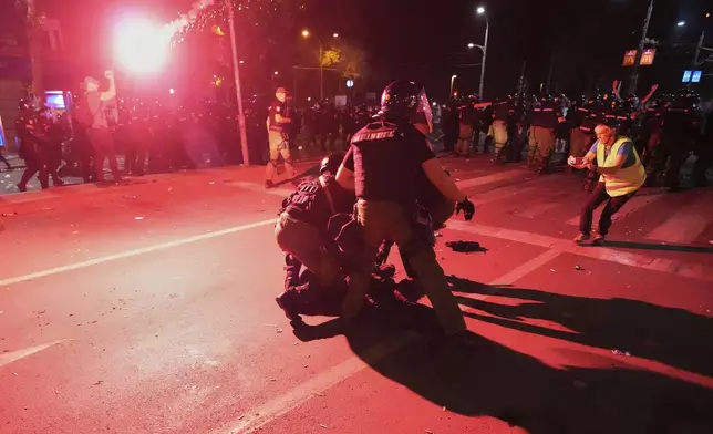 Riot police detain a man after charging protesters at the end of an anti-government rally pressing for an early election after nearly eight months of almost daily anti-corruption demonstrations that have shaken the populist government of President Aleksandar Vucic, in Belgrade, Serbia, Saturday, June 28, 2025. (AP Photo/Darko Vojinovic)