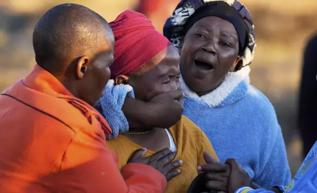 A woman is consoled by community members as bodies of her sister and three daughters were retrieved from inside a one room house, after floods swept through the area in Mthatha, South Africa, Thursday, June 12, 2025. (AP Photo/Themba Hadebe)