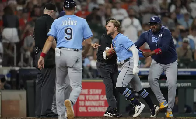 Tampa Bay Rays' Taylor Walls, center, is held back after he's ejected by Umpire Nic Lentz, left, for tapping his helmet after a strike call during the ninth inning of a baseball game against the Houston Astros in Houston, Sunday, June 1, 2025. (AP Photo/Ashley Landis)
