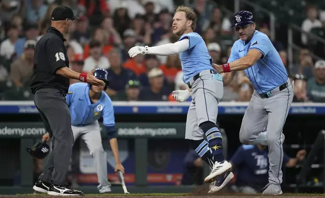Tampa Bay Rays' Taylor Walls, center, runs after umpire Vic Carapazza, left, after he's ejected by Umpire Nic Lentz for tapping his helmet after a strike call during the ninth inning of a baseball game against the Houston Astros in Houston, Sunday, June 1, 2025. (AP Photo/Ashley Landis)