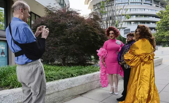 A passerby photographs Tara Hoot, Ricky Rosé and Maria Con Carne outside the Kennedy Center, Wednesday, June 11, 2025, in Washington, before they attend Les Miserables. President Donald Trump and first lady Melania Trump were also attending the performance. (AP Photo/Julia Demaree Nikhinson)