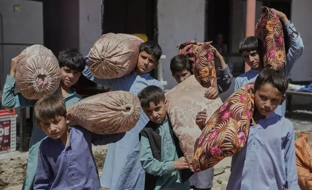 Afghan children from families repatriated from Pakistan carry pillows as they are relocated to their new residence in Kabul, Afghanistan, Tuesday, June 3, 2025. (AP Photo/Ebrahim Noroozi)