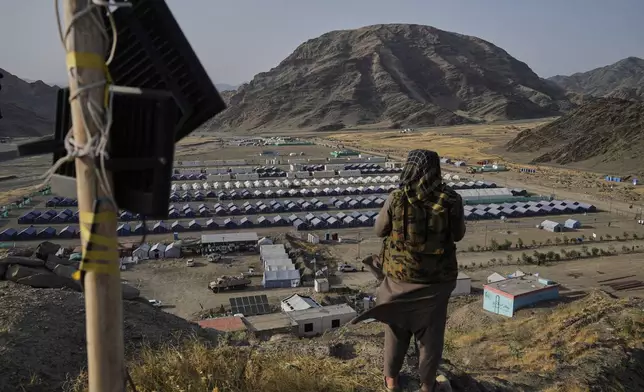 A Taliban fighter stands on a hill overlooking a camp housing Afghan refugees who have been repatriated from Pakistan, near the Pakistan-Afghanistan border, in Torkham, Afghanistan, Saturday, May 31, 2025. (AP Photo/Ebrahim Noroozi)
