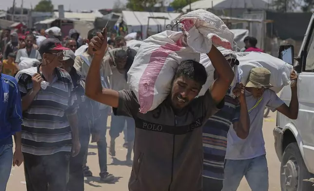 A Palestinian carries a bag containing food and humanitarian aid delivered by the Gaza Humanitarian Foundation, a U.S.-backed organization, in Rafah, southern Gaza Strip, Wednesday, June 11, 2025. (AP Photo/Abdel Kareem Hana)