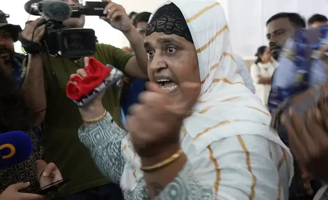 Salma Rafiq Memon, in white scarf, gestures angrily as she speaks to media personnel while waiting for the bodies of four relatives who died in the Air India plane crash, at a hospital in Ahmedabad, India, Saturday, June 14, 2025. (AP Photo/Rafiq Maqbool)