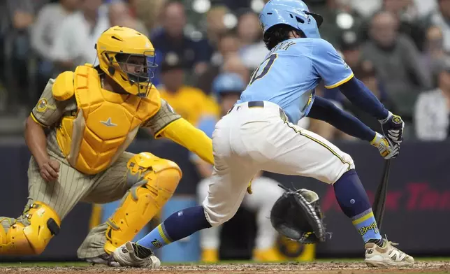 San Diego Padres' Elias Díaz, left, loses his glove after committing catcher interference against Milwaukee Brewers' Sal Frelick, right, during the eighth inning of a baseball game Saturday, June 7, 2025, in Milwaukee. (AP Photo/Aaron Gash)