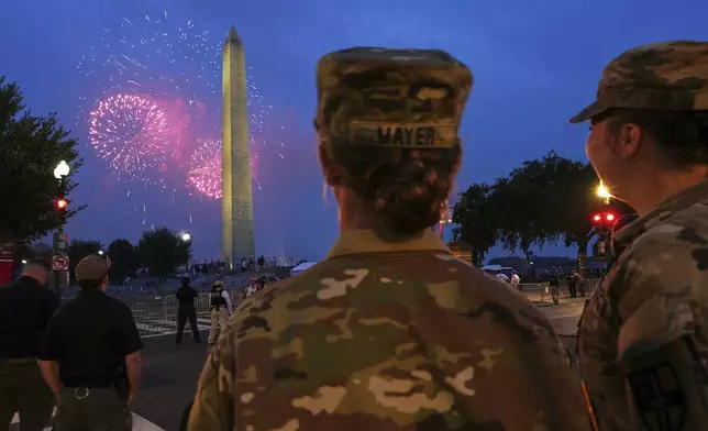 U.S. Army 2nd Lt. Hayle Mayer, left, and Corporal Addison Merrell, watch fireworks at the Washington Monument while attending a military parade commemorating the Army's 250th anniversary and coinciding with President Donald Trump's 79th birthday, Saturday, June 14, 2025, in Washington. (AP Photo/Jacquelyn Martin)