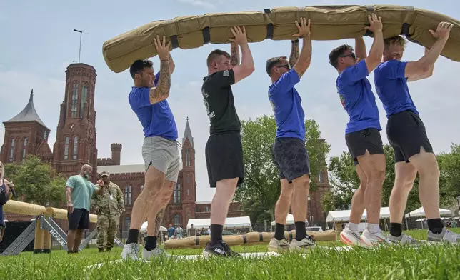 Army SSG Jason Craig, from left, Army Sgt. Blake Oakley, Army 1st Lt. Lukas Nicoloff, Army 1st Lt. Michael Ramirez and Army 1st Lt. Sean Buck lift a weighted "worm" as they practice ahead of the Army Fittest Squad competition, Friday, June 13, 2025, by the Smithsonian Castle on the National Mall in Washington, during preparations for an upcoming military parade commemorating the Army's 250th anniversary and coinciding with President Donald Trump's 79th birthday. (AP Photo/Jacquelyn Martin).