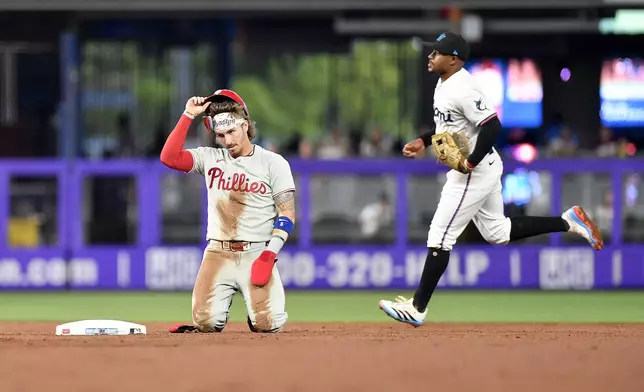 Philadelphia Phillies' Bryson Stott, left, reacts after being called out after trying to steal second base as Miami Marlins Xavier Edwards runs to the dugout during the second inning of a baseball game, Thursday, June 19, 2025, in Miami. (AP Photo/Michael Laughlin)