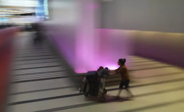 A traveler pushes a luggage cart through the international arrivals area at the international airport in Los Angeles, Friday, June 6, 2025. (AP Photo/Jae C. Hong)