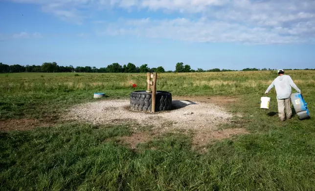 Bobby Carey fills mineral feeders for his herd of cattle at Oakland Farm, Monday, June 23, 2025, in Bourbon County, Ky. (AP Photo/Michael Swensen)