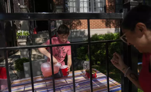 Robby, 12, who did not want to give his last name, sells lemonade in his front yard on a hot Friday, June 20, 2025, in Chicago. (AP Photo/Erin Hooley)
