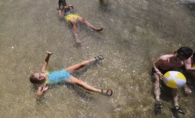 With temperatures hovering near 100 degrees, children cool off in the Frog Pond, on Boston Common, Tuesday, June 24, 2025, in Boston. (AP Photo/Charles Krupa)