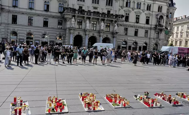 People pay a moment of silence on the main square after a former student opened fire the day before at a school fatally wounding several people and injuring many others before taking his own life, Graz, Austria, Wednesday, June 11, 2025. (AP Photo/Darko Bandic)