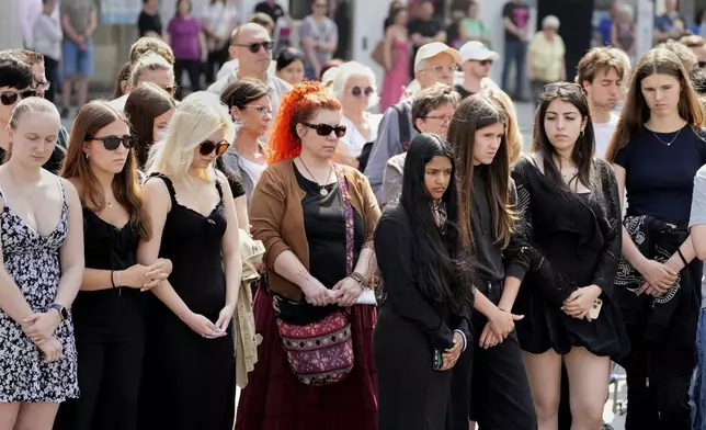 People pay a moment of silence on the main square after a former student opened fire the day before at a school fatally wounding several people and injuring many others before taking his own life, Graz, Austria, Wednesday, June 11, 2025. (AP Photo/Darko Bandic)