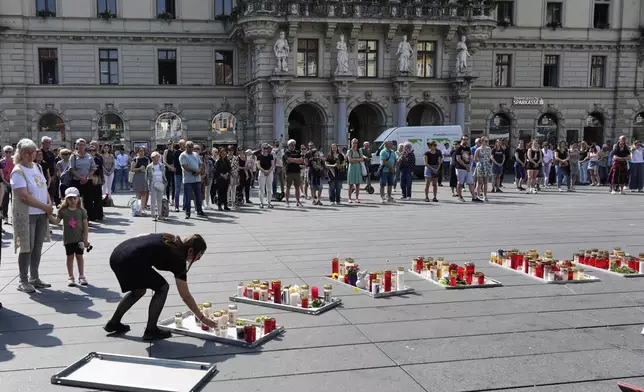 People pay a moment of silence on the main square after a former student opened fire the day before at a school fatally wounding several people and injuring many others before taking his own life, Graz, Austria, Wednesday, June 11, 2025. (AP Photo/Darko Bandic)
