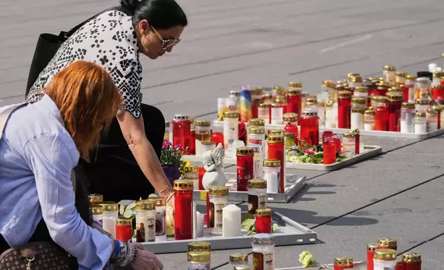 People light candles on the main square after a former student opened fire the day before at a school fatally wounding several people and injuring many others before taking his own life, Graz, Austria, Wednesday, June 11, 2025. (AP Photo/Darko Bandic)