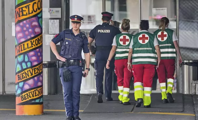 A police officer guards the entrance of a school where a former student opened fire the day before fatally wounding 10 people and injuring many others before taking his own life, Graz, Austria, Wednesday, June 11, 2025. (AP Photo/Darko Bandic)