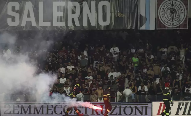 Firefighters tend to a flare thrown onto the pitch during a playoff between Sampdoria and Salernitana to stay in Serie B, which caused the suspension of the match, at the at the Arechi Stadium in Salerno, southern Italy, Sunday, July 22, 2025. (Alessandro Garofalo/LaPresse via AP)