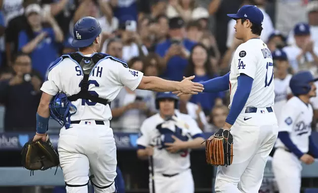 Los Angeles Dodgers starting pitcher Shohei Ohtani, right, shakes hands with catcher Will Smith during the first inning of a baseball game against the San Diego Padres, Monday, June 16, 2025, in Los Angeles. (AP Photo/Kyusung Gong)