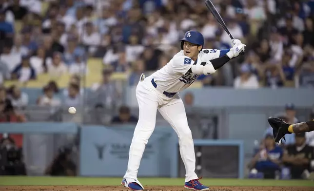 Los Angeles Dodgers' Shohei Ohtani takes a hit by pitch during the third inning of a baseball game against the San Diego Padres in Los Angeles, Tuesday, June 17, 2025. (AP Photo/Kyusung Gong)