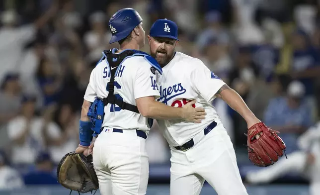 Los Angeles Dodgers relief pitcher Kirby Yates, right, and catcher Will Smith celebrate the team's win over the San Diego Padres in a baseball game, in Los Angeles, Monday, June 16, 2025. (AP Photo/Kyusung Gong)