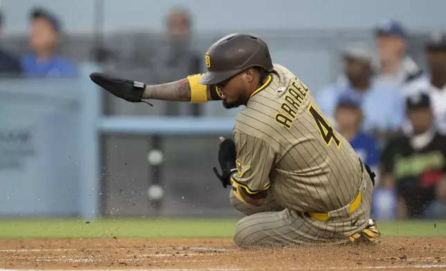 San Diego Padres' Luis Arraez slides to score on an RBI single by Gavin Sheets during the first inning of a baseball game against the Los Angeles Dodgers in Los Angeles, Tuesday, June 17, 2025. (AP Photo/Kyusung Gong)