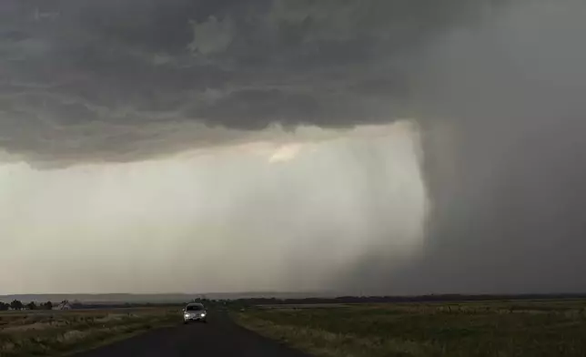 A car moves away from an approaching storm with a rain shaft during a Project ICECHIP operation on Tuesday, June 3, 2025, near Tipton, Okla. (AP Photo/Carolyn Kaster)