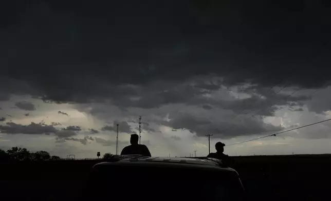 Victor Gensini, Northern Illinois University meteorology professor and a lead scientist of Project ICECHIP, right, and Logan Bundy, PhD Candidate at NIU and ICECHIP IOP assistant, left, stand at the command vehicle watching an approaching storm Tuesday, June 3, 2025, in Scotland, Texas. (AP Photo/Carolyn Kaster)
