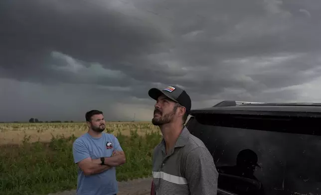 Victor Gensini, Northern Illinois University meteorology professor and a lead scientist of Project ICECHIP, right, and Logan Bundy, PhD Candidate at NIU and ICECHIP IOP assistant, look at cloud formations during a Project ICECHIP operation, Tuesday, June 3, 2025, south of Tipton, Okla. (AP Photo/Carolyn Kaster)