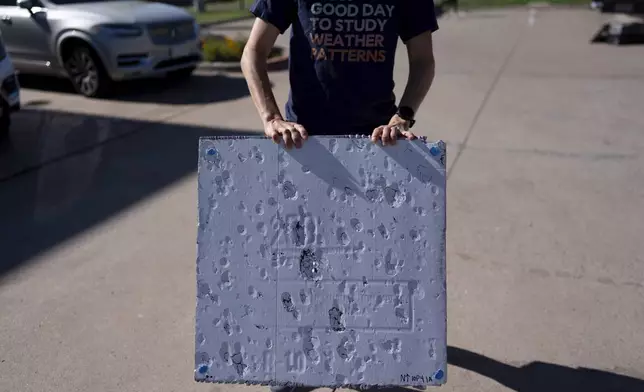 Hannah Vagasky holds a foam board hail pad covered with impact dents in a parking lot Tuesday, June 3, 2025, in Shamrock, Texas, as the team prepares for a day of hailstorm chasing. The hail pad is used to measure the size, angle of impact and intensity of hail. (AP Photo/Carolyn Kaster)