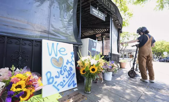 A man looks at signs left in front the restaurant Buona Forchetta, the site of a recent ICE operation in the neighborhood of South Park, Monday, June 2, 2025, in San Diego. (AP Photo/Gregory Bull)