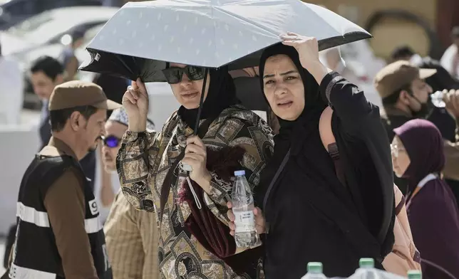 Egyptian pilgrims share an umbrella outside the Grand Mosque during the annual hajj pilgrimage at the holy city of Mecca, Saudi Arabia, Tuesday, June 3, 2025. (AP Photo/Amr Nabil)