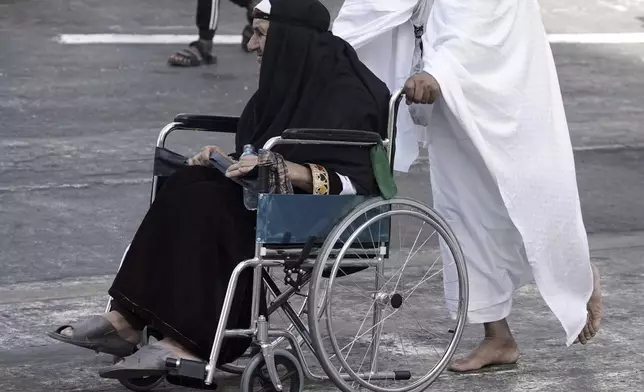 An Afghan elderly pilgrim on a wheel chair is pushed by her son, during the annual hajj pilgrimage in Mecca, Saudi Arabia, Tuesday, June 3, 2025. (AP Photo/Amr Nabil)