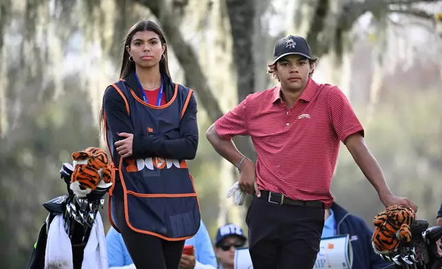 FILE - Sam Woods, left, and Charlie Woods wait for their father Tiger Woods to tee off on the 14th hole during the final round of the PNC Championship golf tournament, in Orlando, Fla., Dec. 22, 2024. (AP Photo/Phelan M. Ebenhack, File)