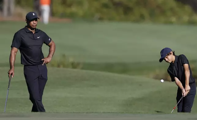 FILE - Tiger Woods, left, watches his son Charlie chip onto the fifth green during the first round of the PNC Championship golf tournament, in Orlando, Fla., Dec. 17, 2021. (AP Photo/Scott Audette, File)