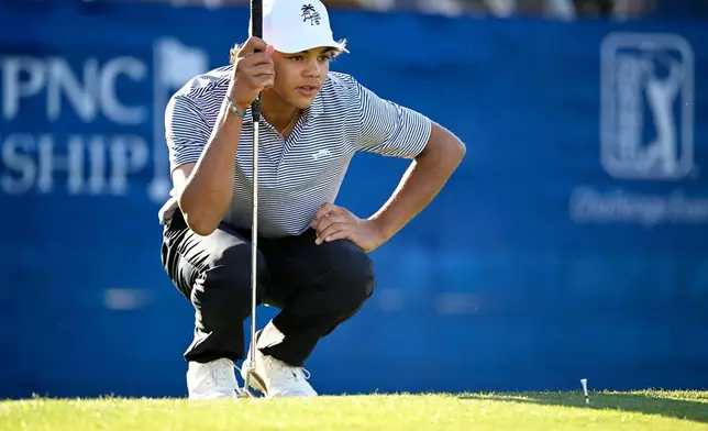 FILE - Charlie Woods lines up a putt on the 18th green during the first round of the PNC Championship golf tournament, in Orlando, Fla., Dec. 21, 2024. (AP Photo/Phelan M. Ebenhack, File)