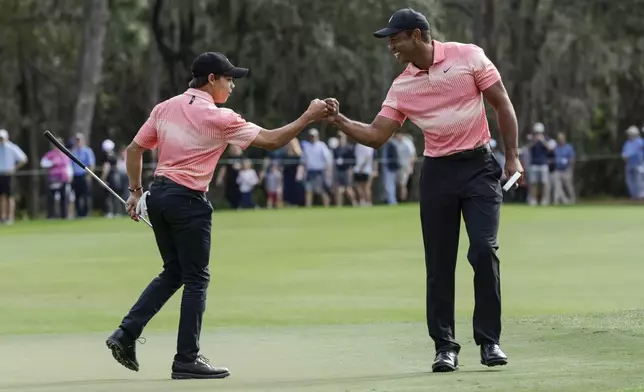 FILE - Tiger Woods, right and his son Charlie Woods bump fists on the ninth green during the first round of the PNC Championship golf tournament in Orlando, Fla., Dec. 17, 2022. (AP Photo/Kevin Kolczynski, File)