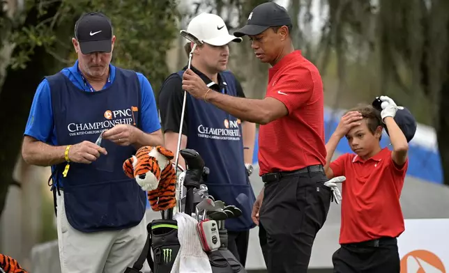 FILE - Tiger Woods and his son Charlie wait to hit their tee shots on the 10th hole as their caddies Joe LaCava, left, and Joe LaCava Jr. watch during the final round of the PNC Championship golf tournament, in Orlando, Fla., Dec. 20, 2020. (AP Photo/Phelan M. Ebenhack, File)