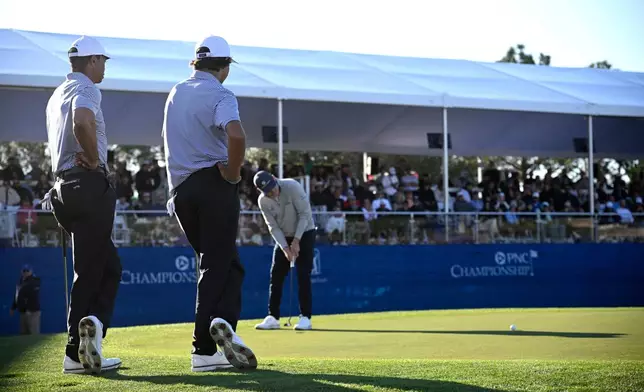 FILE - Tiger Woods, left, and his son Charlie Woods watch as Justin Leonard putts on the 18th green during the first round of the PNC Championship golf tournament, in Orlando, Fla., Dec. 21, 2024. (AP Photo/Phelan M. Ebenhack, File)