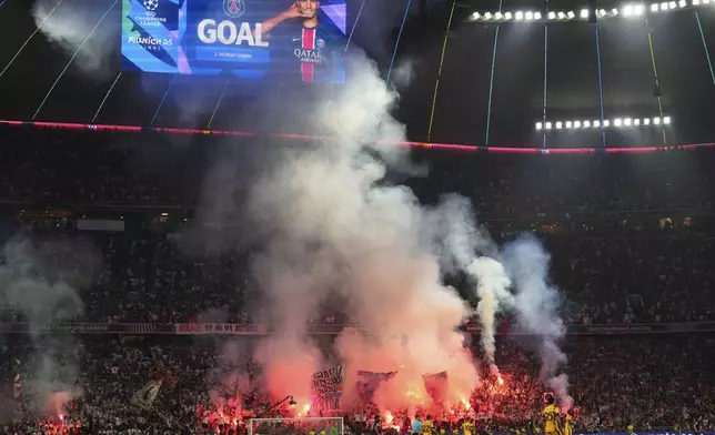 PSG's fans light flares after Achraf Hakimi scored his side's first goal during the Champions League final soccer match between Paris Saint-Germain and Inter Milan at the Allianz Arena in Munich, Germany, Saturday, May 31, 2025. (AP Photo/Matthias Schrader)
