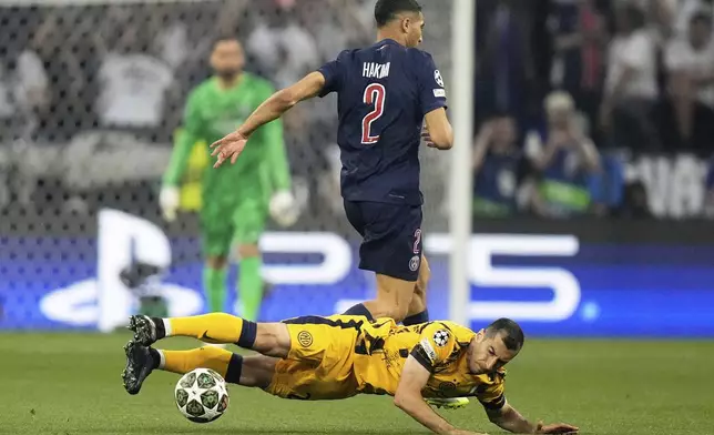 Inter Milan's Henrikh Mkhitaryan, bottom, falls after challenging for the ball with PSG's Achraf Hakimi during the Champions League final soccer match between Paris Saint-Germain and Inter Milan at the Allianz Arena in Munich, Germany, Saturday, May 31, 2025. (AP Photo/Matthias Schrader)