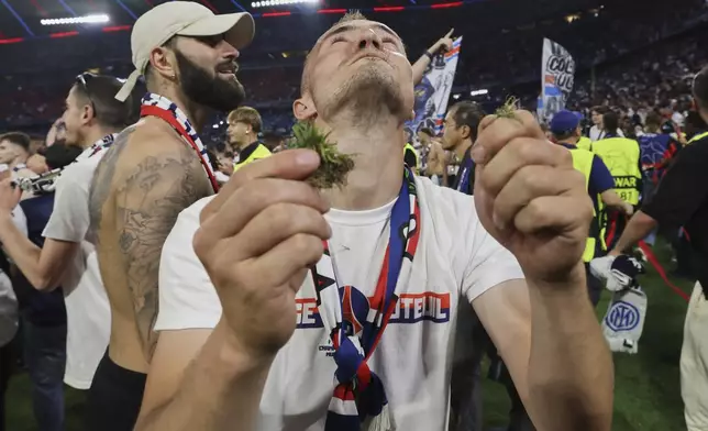 A PSG fan holds the grass from the pitch after the Champions League final soccer match between Paris Saint-Germain and Inter Milan at the Allianz Arena in Munich, Germany, Saturday, May 31, 2025. (AP Photo/Alexandra Beier)